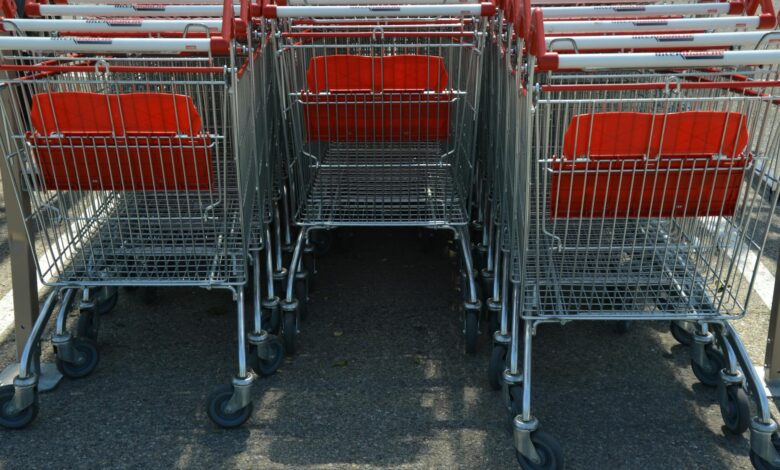 Shopping cart in grocery store aisle with shelves of products