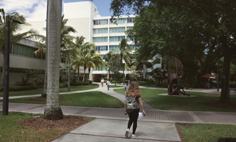 Students walking across university campus courtyard with historic buildings in background