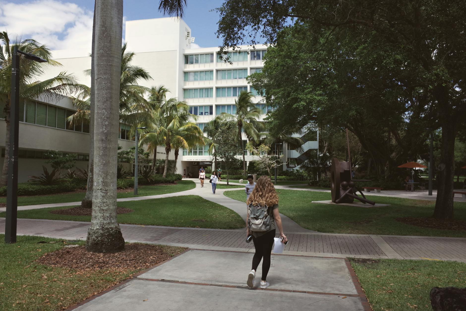 Students walking across university campus courtyard with historic buildings in background