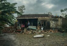 Damaged house with fallen tree and debris from severe storm showing insurance claim scenario