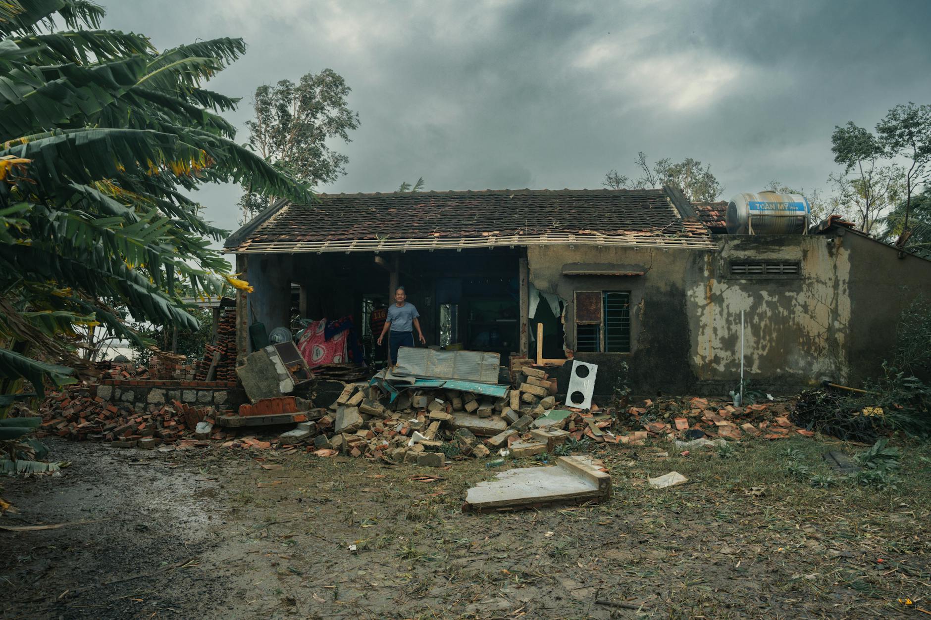 Damaged house with fallen tree and debris from severe storm showing insurance claim scenario