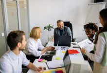Professional office workers gathered around conference table in discussion