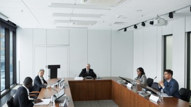 Professional conference room with people in business attire seated around a large table during a formal meeting