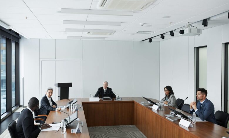 Professional conference room with people in business attire seated around a large table during a formal meeting
