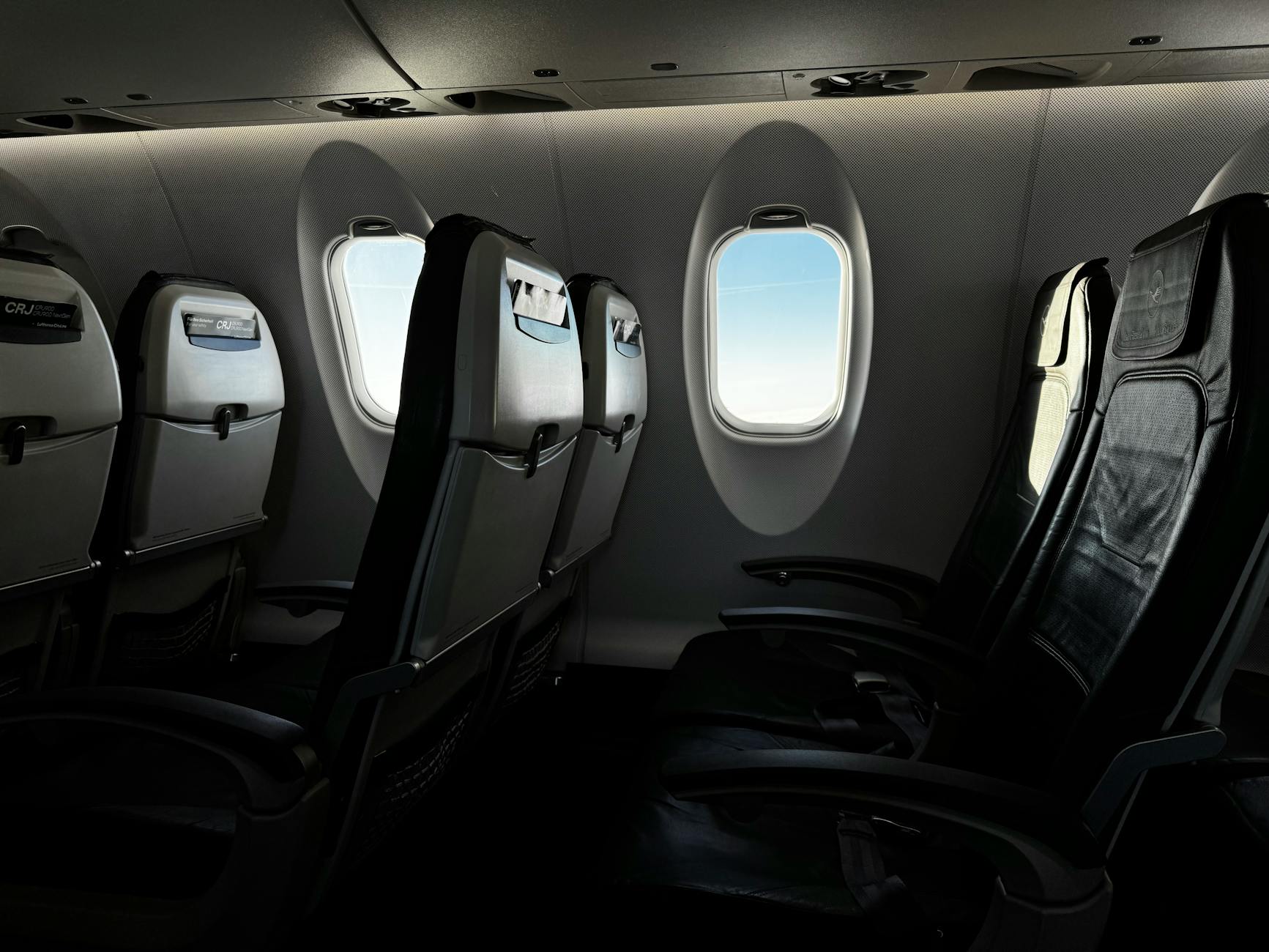 Modern airline cabin interior showing rows of passenger seats with overhead compartments