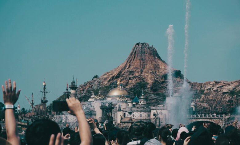 Large crowds of people walking through a busy theme park area during daytime