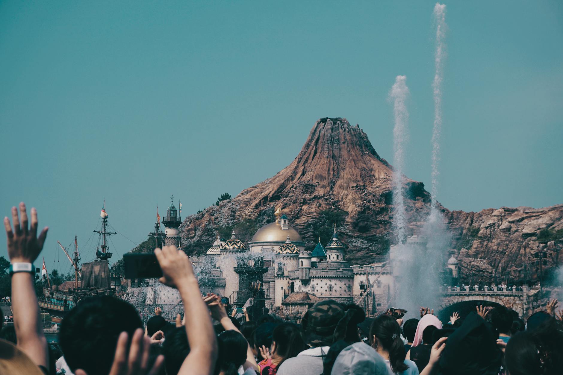 Large crowds of people walking through a busy theme park area during daytime