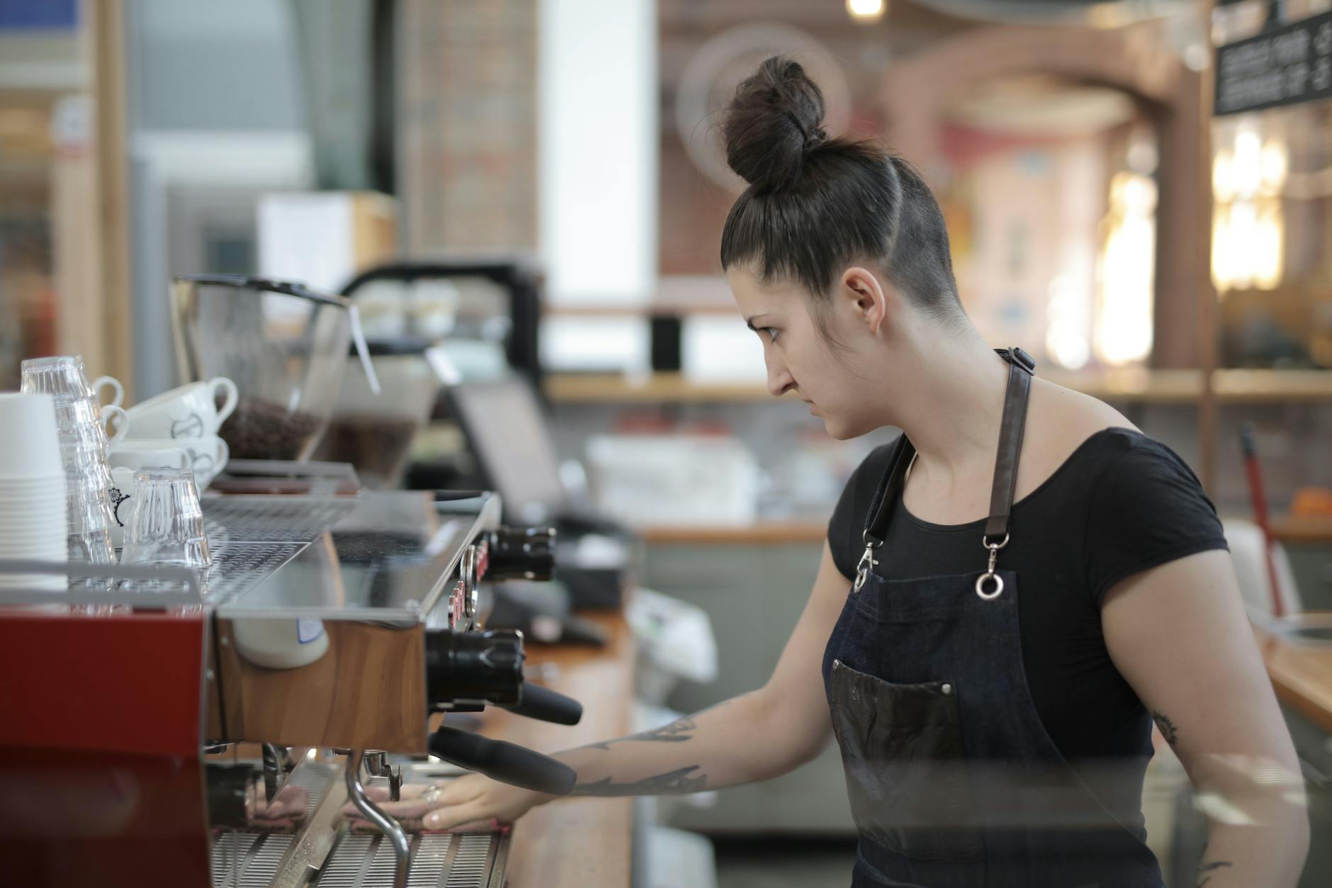 Professional barista preparing coffee drink behind modern cafe counter