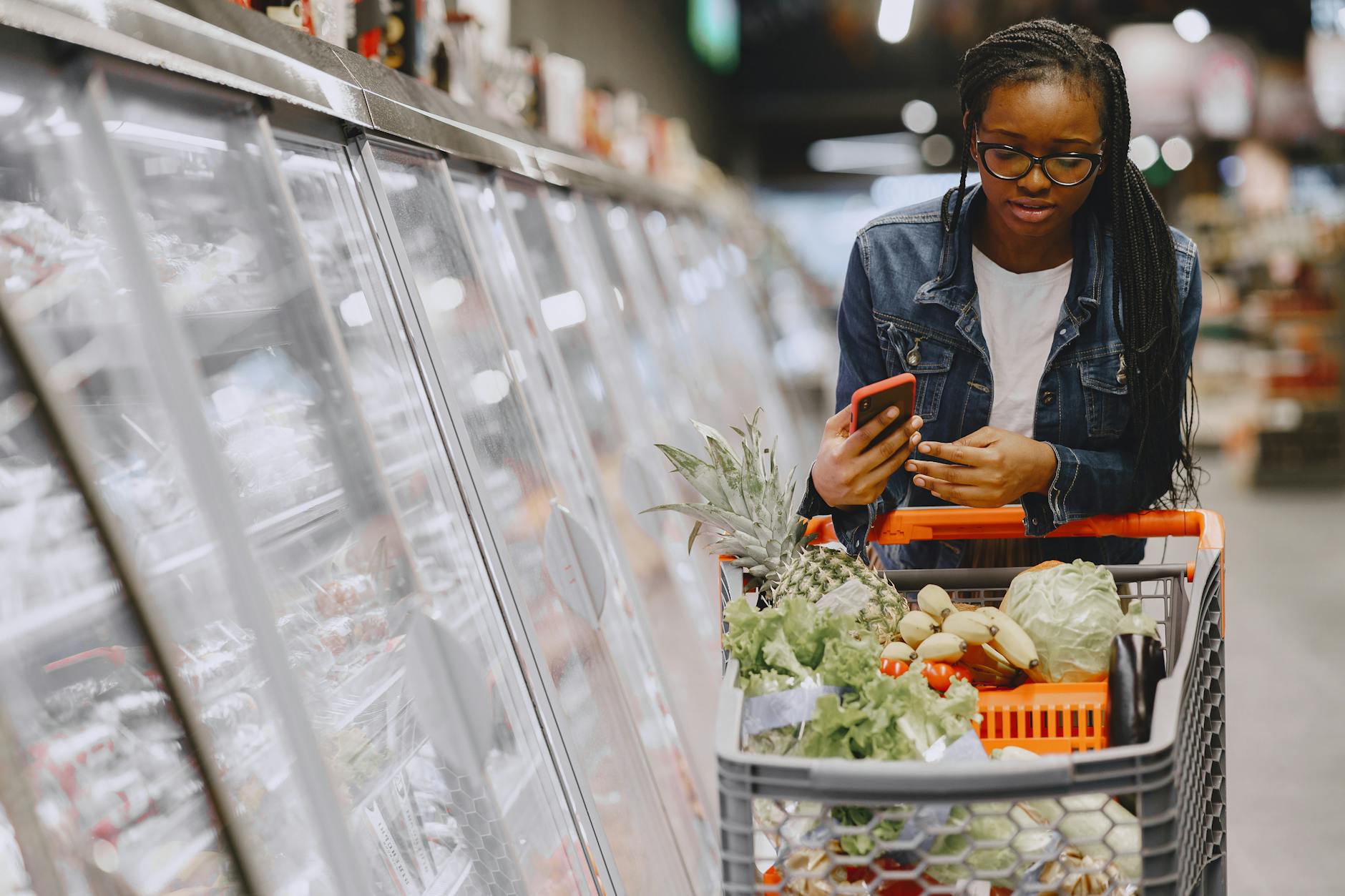 Customer shopping with full cart in grocery store aisle