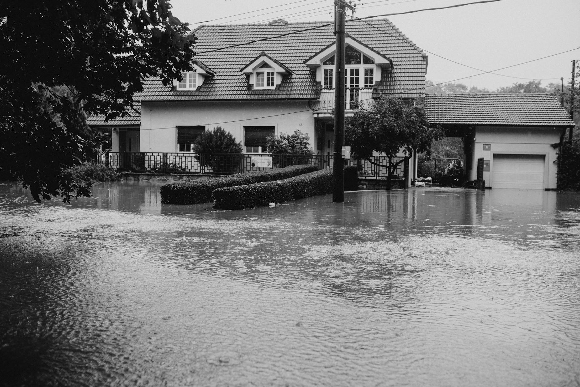 Flood-damaged house with debris around foundation showing disaster aftermath