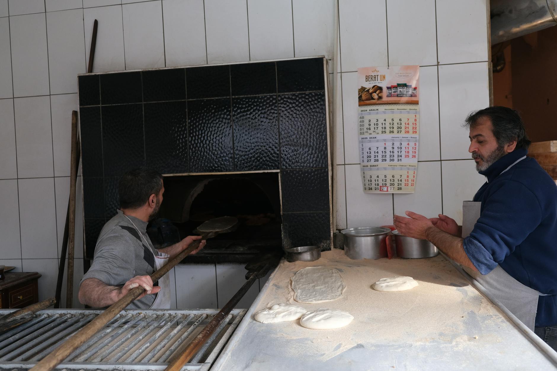 Bakers working together in a commercial kitchen, kneading dough and preparing baked goods