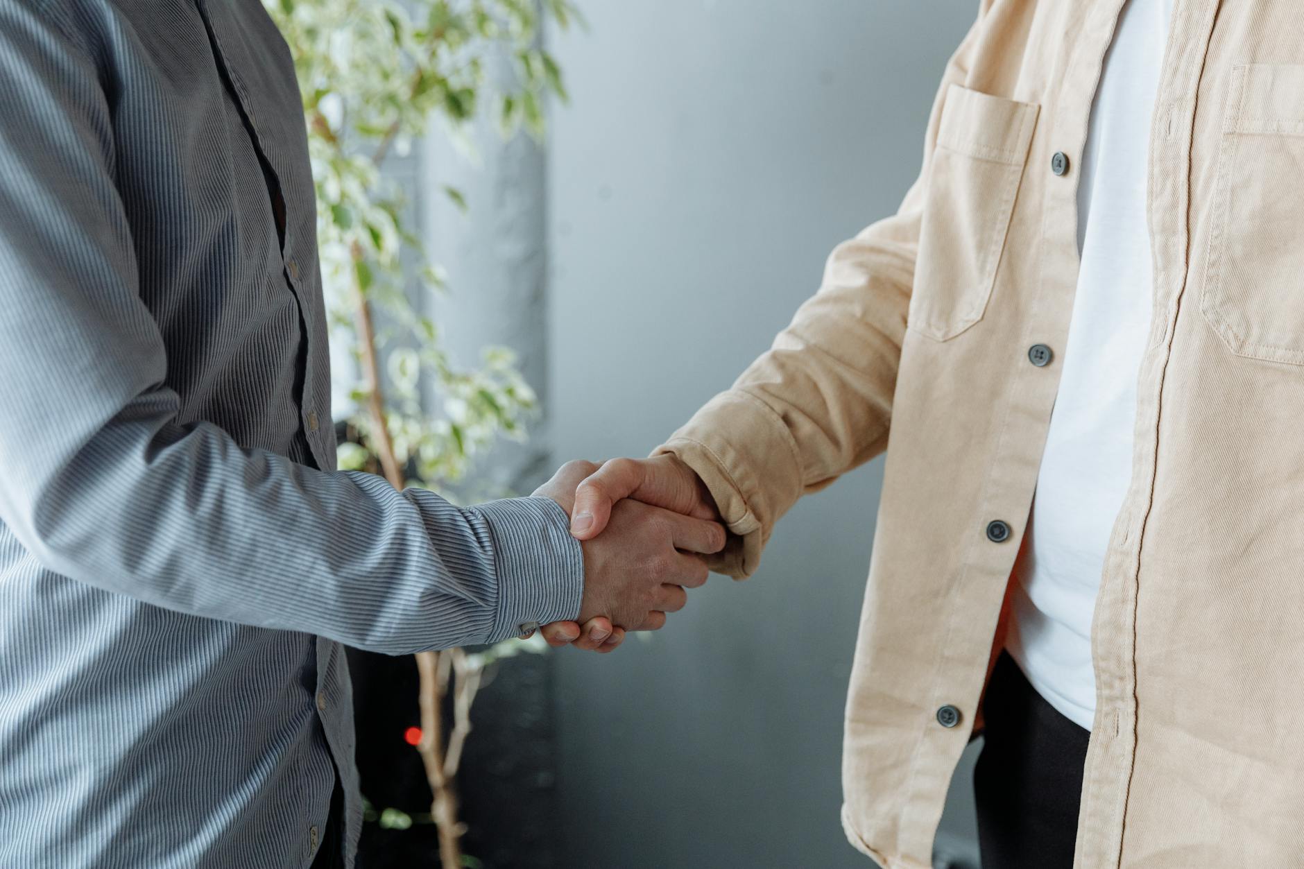 Professional handshake between two business people in modern office setting representing successful hiring
