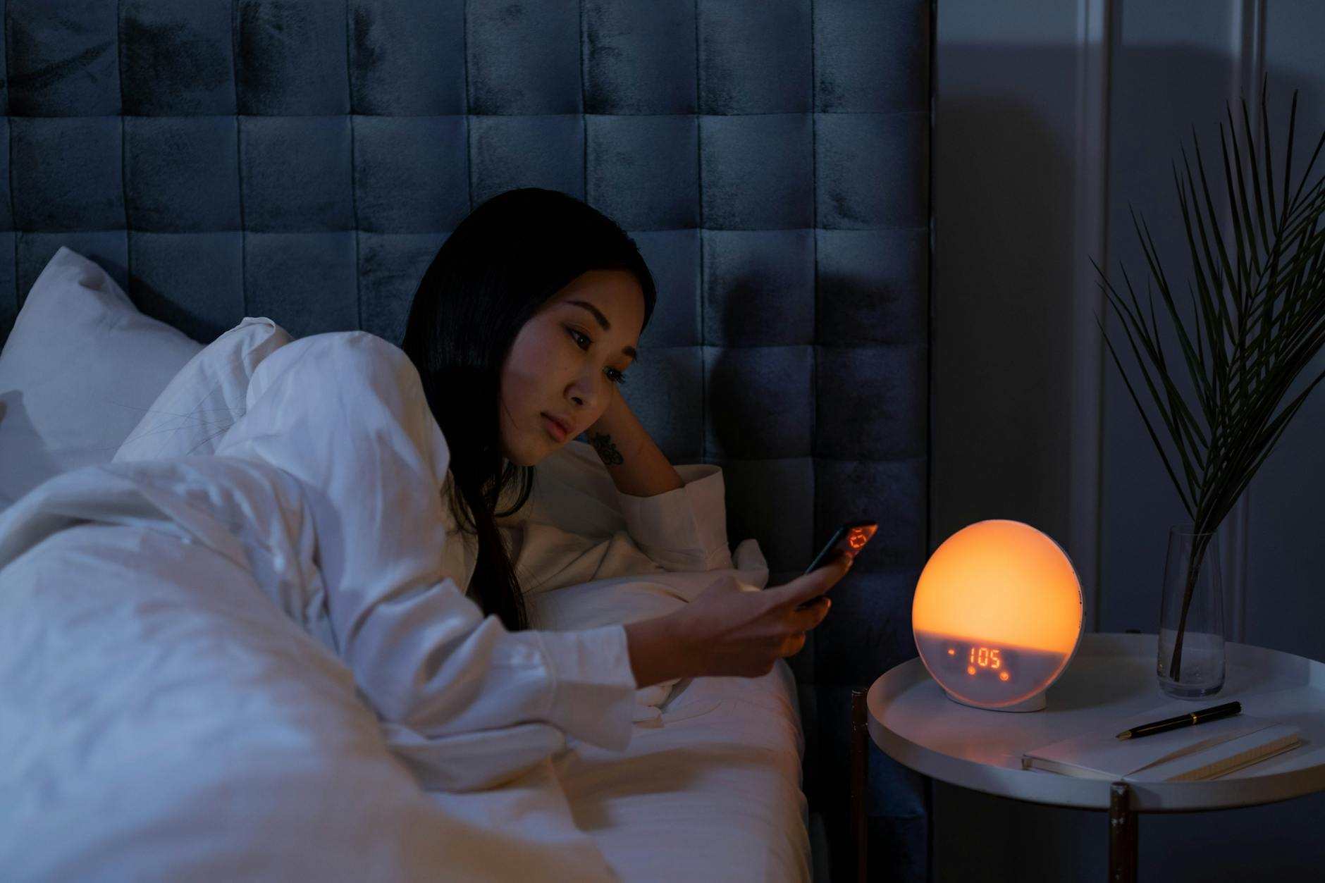 Bedroom nightstand with smartphone displaying sleep tracking app interface