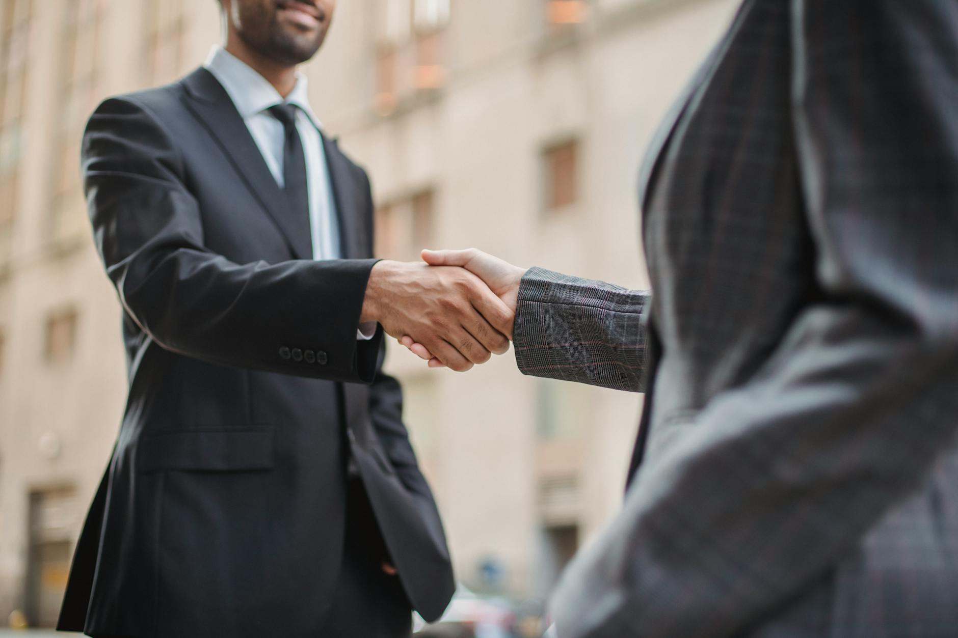 Two people shaking hands over documents in a professional business meeting setting