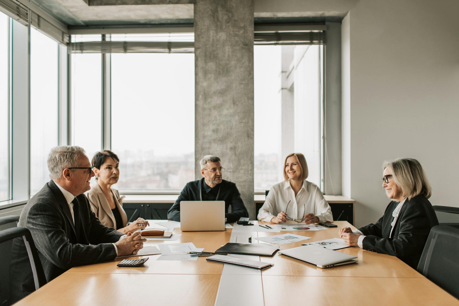 Business professionals in meeting discussing financial documents and charts on conference room table
