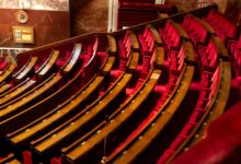 Empty Senate chamber with rows of wooden desks under a domed ceiling
