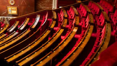 Empty Senate chamber with rows of wooden desks under a domed ceiling