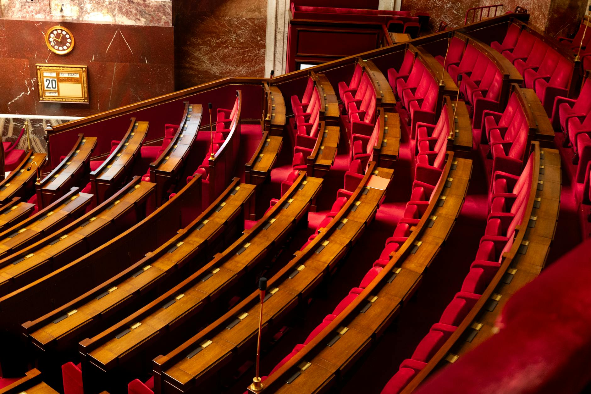 Empty Senate chamber with rows of wooden desks under a domed ceiling