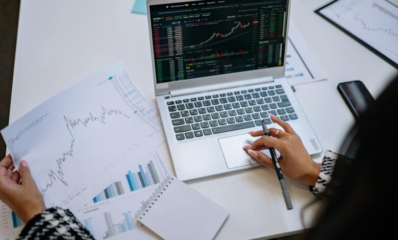 Financial advisor reviewing investment portfolio at a desk with multiple monitors