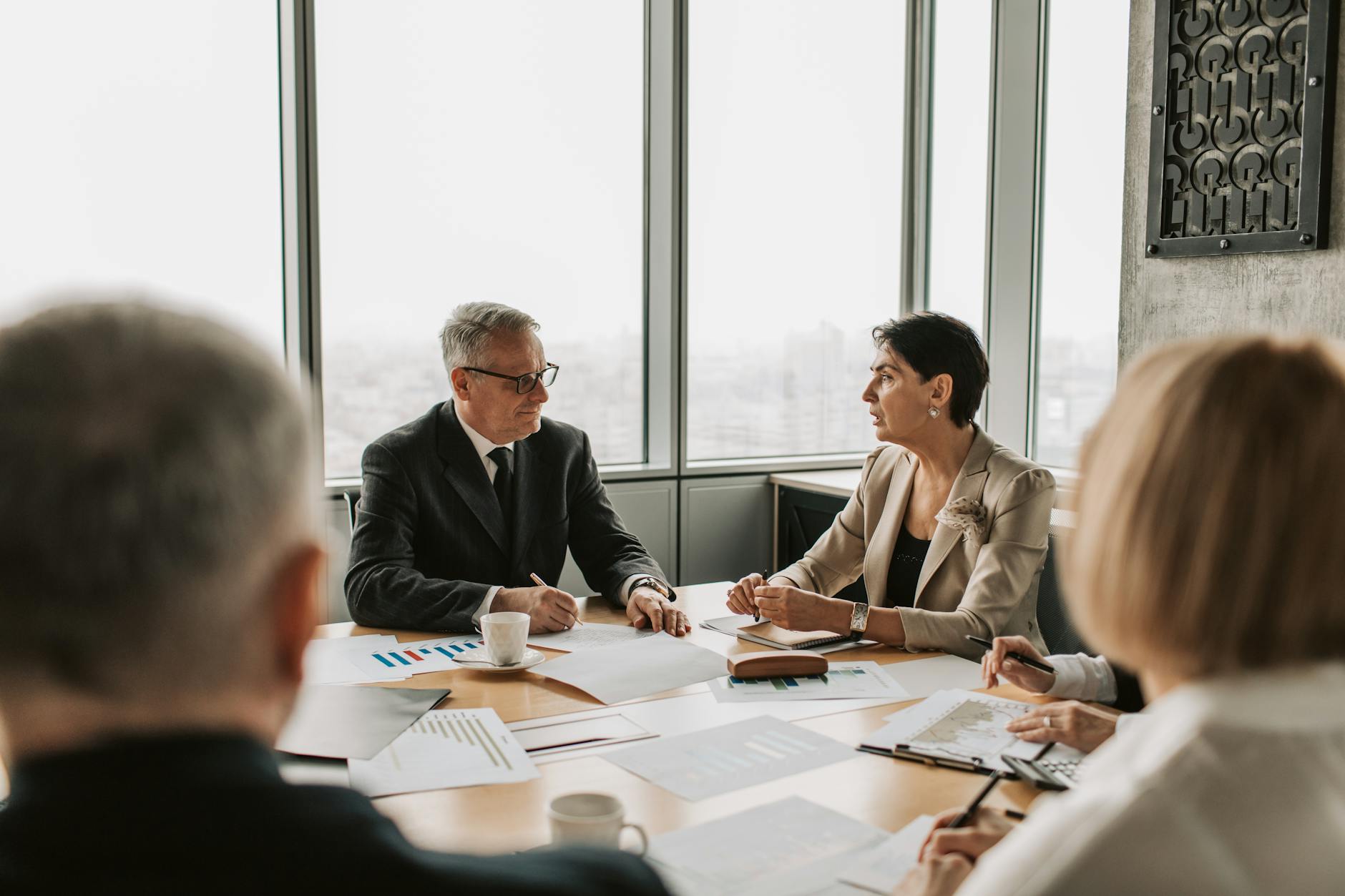 Business professionals reviewing financial documents at a corporate meeting table