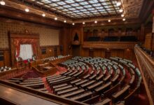 Empty senate chamber with rows of desks and American flag