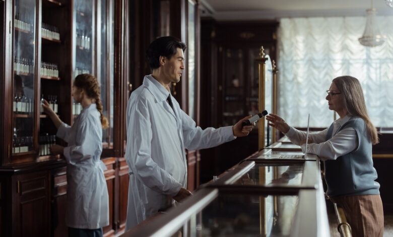 Independent pharmacist standing behind a prescription counter in a small community pharmacy