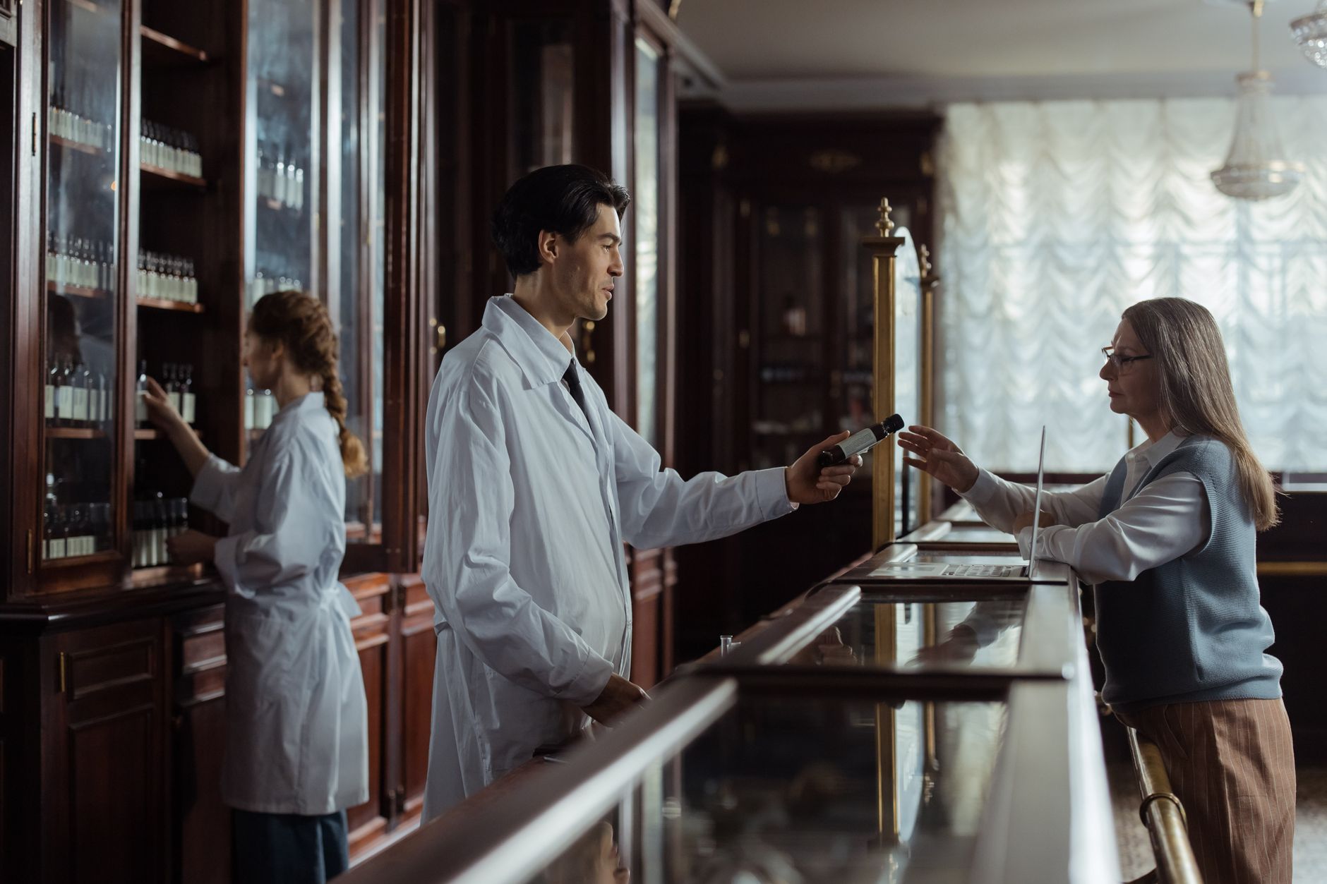 Independent pharmacist standing behind a prescription counter in a small community pharmacy