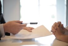 Insurance broker sitting at office desk reviewing policy documents with a client