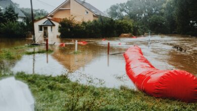 Residential neighborhood streets submerged in floodwater with homes visible in background