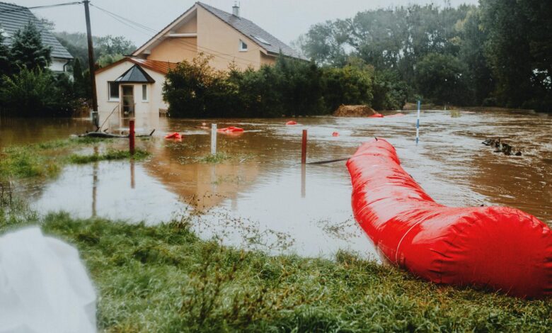 Residential neighborhood streets submerged in floodwater with homes visible in background