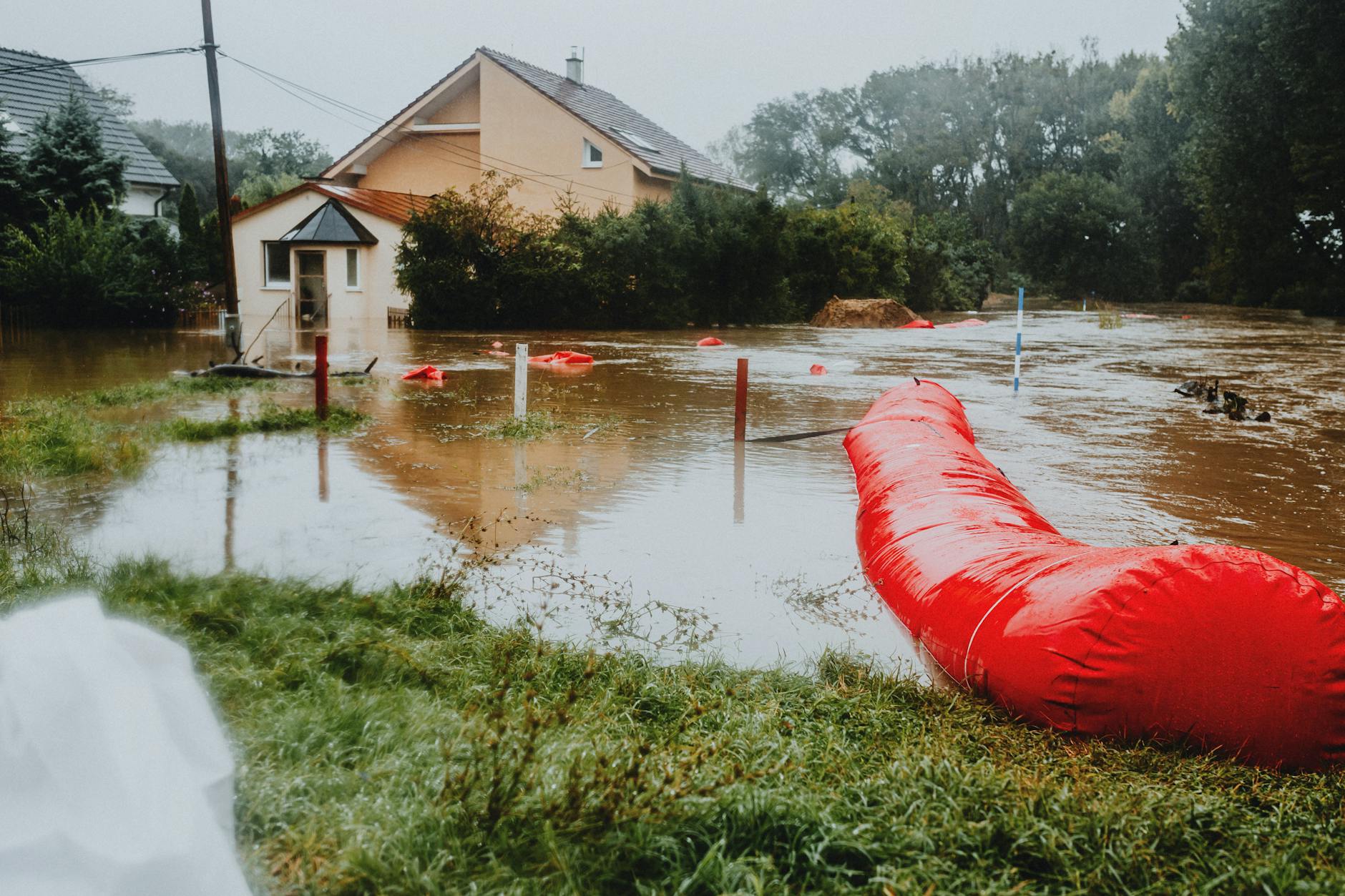 Residential neighborhood streets submerged in floodwater with homes visible in background