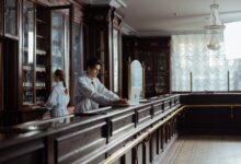 A pharmacist working behind a specialty pharmacy counter reviewing prescription records