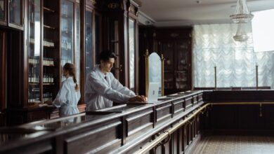 A pharmacist working behind a specialty pharmacy counter reviewing prescription records