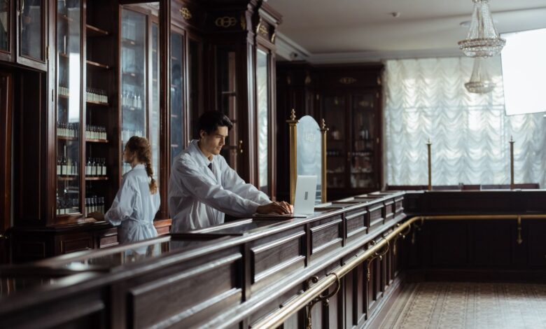 A pharmacist working behind a specialty pharmacy counter reviewing prescription records