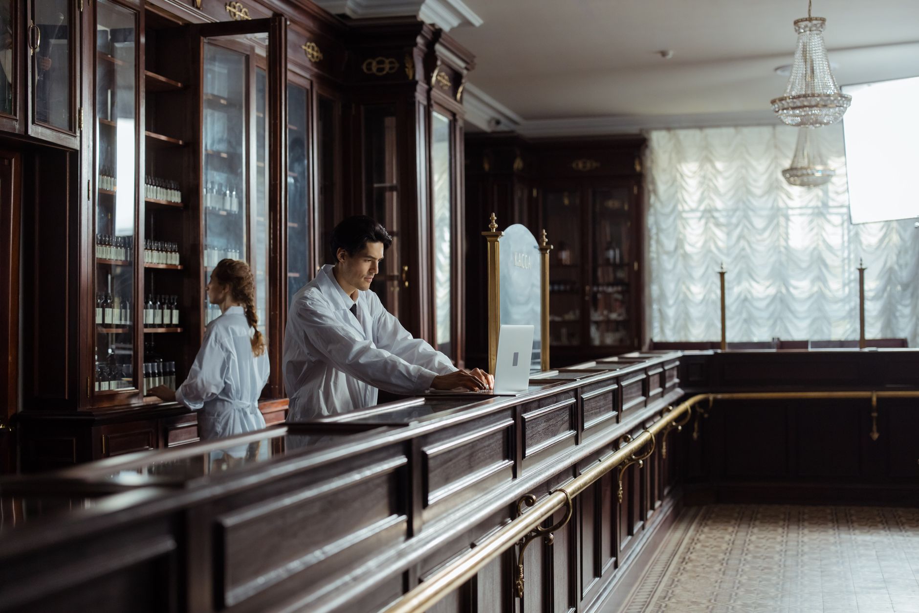 A pharmacist working behind a specialty pharmacy counter reviewing prescription records
