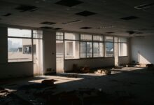 Empty floors inside a vacant commercial office tower with dark windows and unused workstations