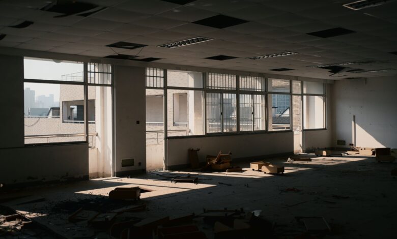 Empty floors inside a vacant commercial office tower with dark windows and unused workstations