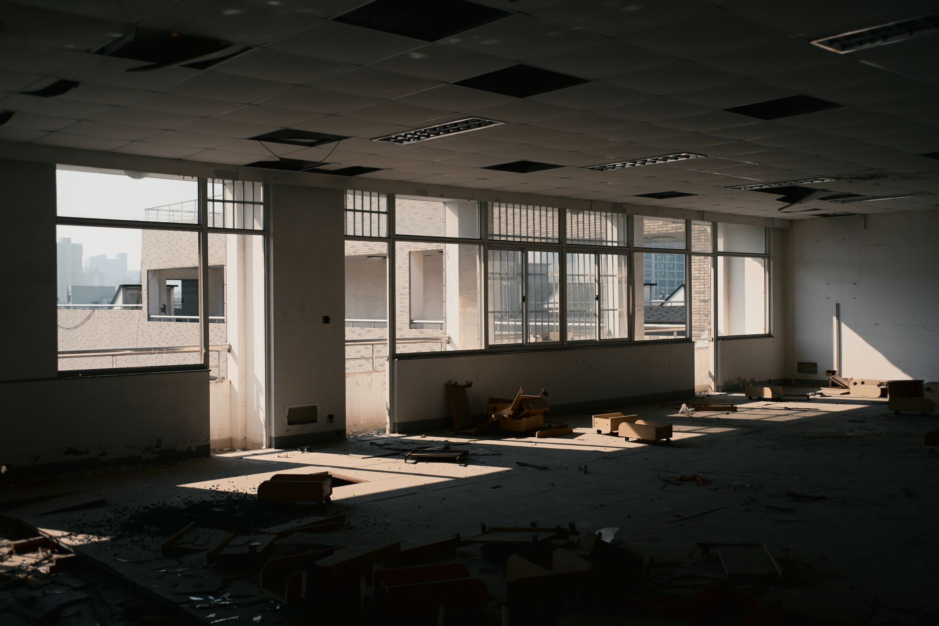 Empty floors inside a vacant commercial office tower with dark windows and unused workstations