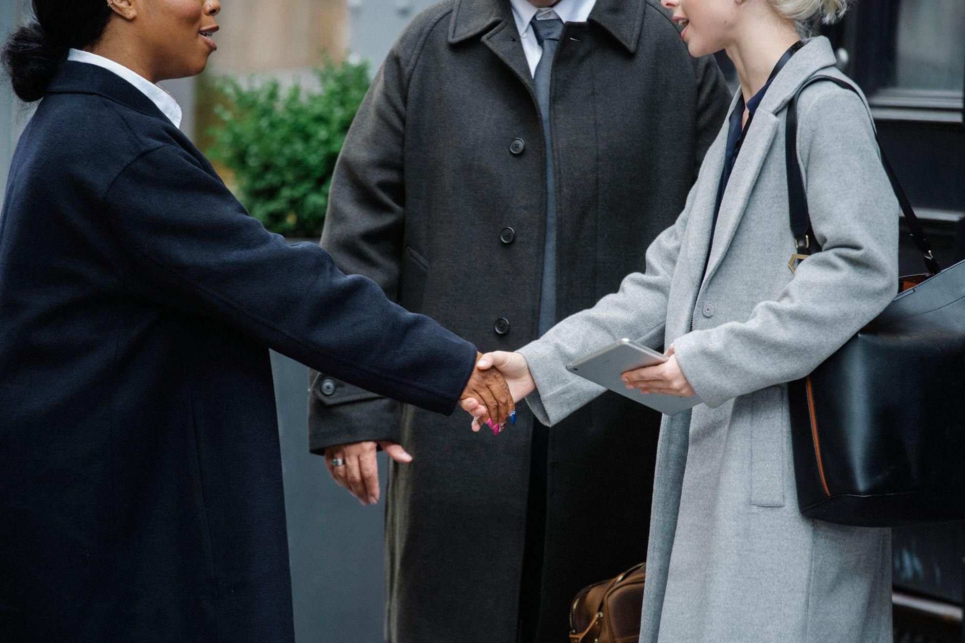 Two professionals shaking hands across a desk during a business meeting