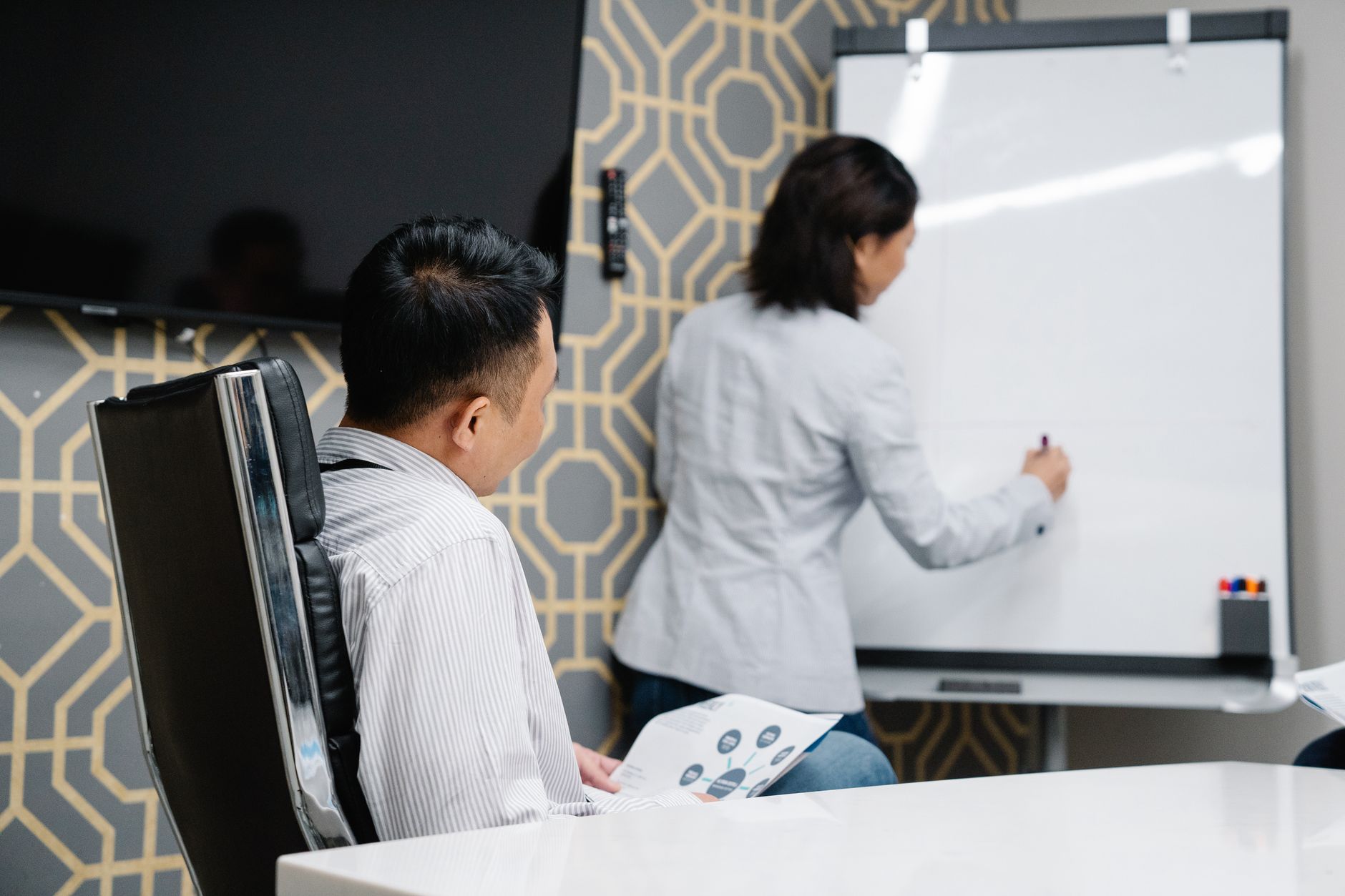 Marketing professional writing on a whiteboard during a strategy session