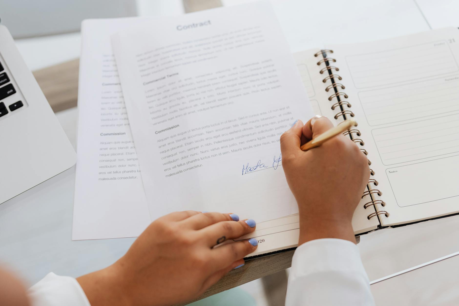 Person signing a formal business contract document at a desk