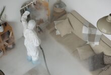 A pest control technician in uniform inspecting a residential property