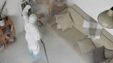 A pest control technician in uniform inspecting a residential property