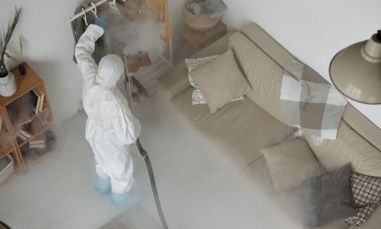 A pest control technician in uniform inspecting a residential property