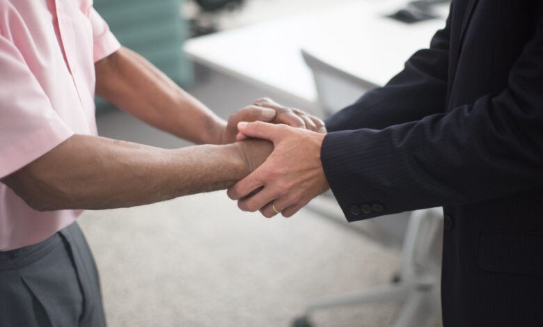 Two professionals reviewing documents at a conference table representing a business merger discussion