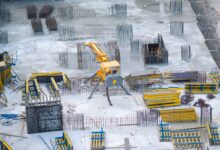 Aerial view of a large commercial construction site with cranes and framework