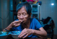 A home health aide assisting an elderly patient in a residential setting