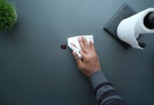 Commercial cleaner wiping down an office desk in a modern workspace