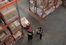 Workers in high-visibility vests inside a large industrial warehouse facility