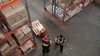Workers in high-visibility vests inside a large industrial warehouse facility